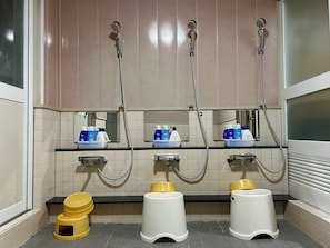 Baño público con tres lavamanos, dos inodoros y tres duchas.
