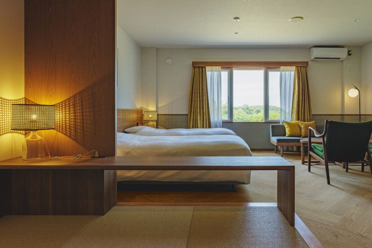 A hotel room with a bed, desk, chair, and a TV.