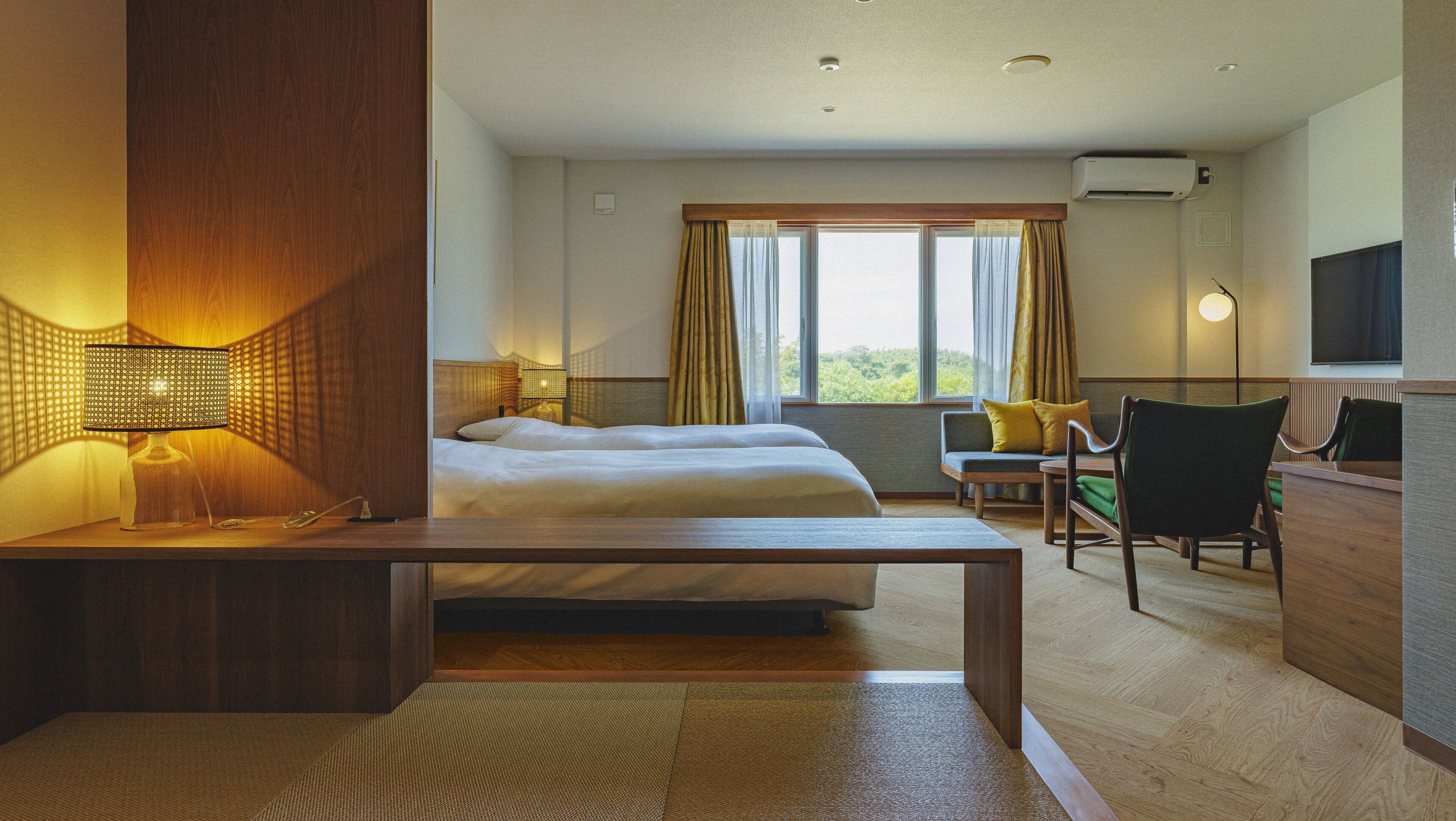 A hotel room with a bed, a desk, a chair, a TV, and a window with curtains.