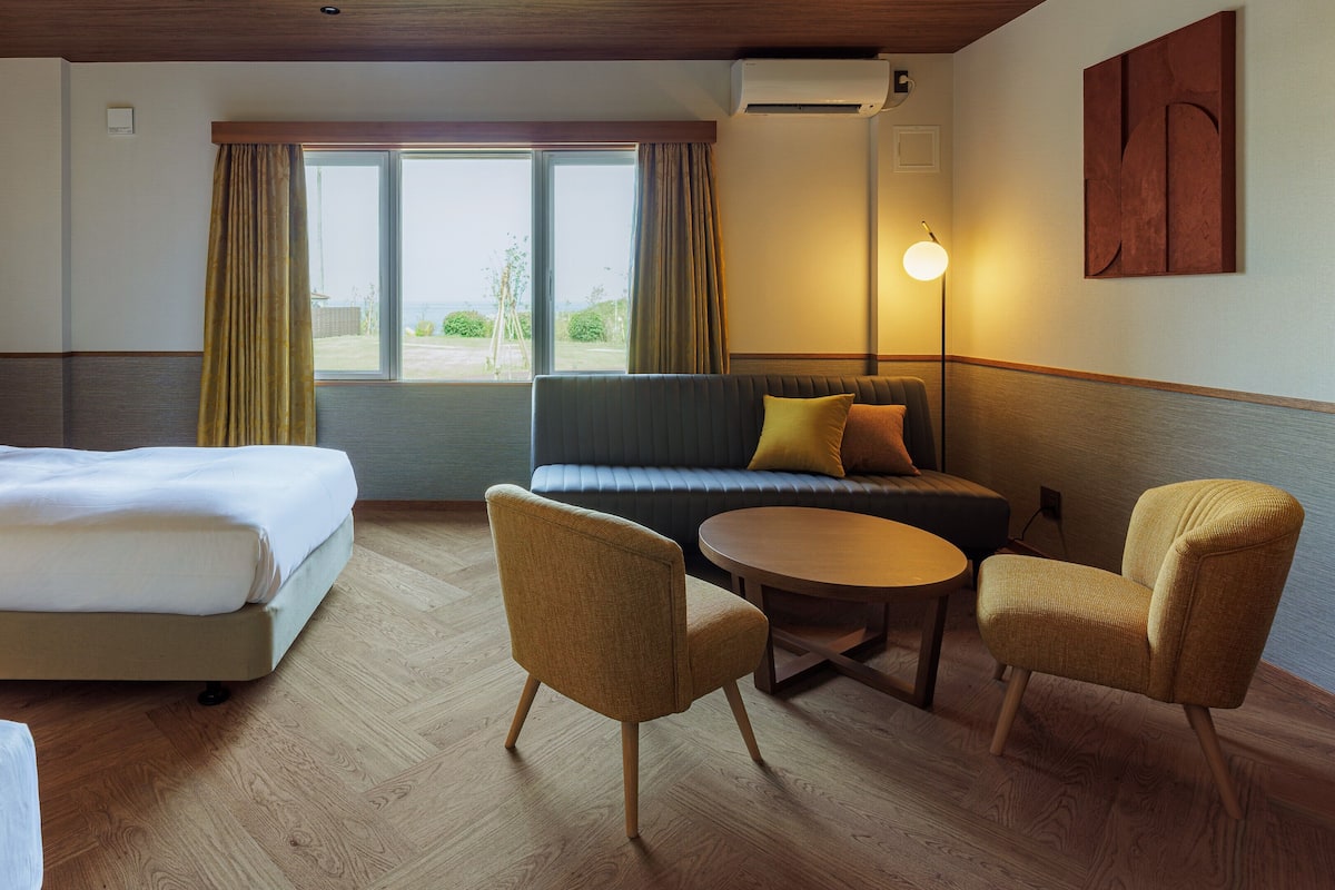 Quarto de hotel com cama, sofá, mesa e cadeiras.