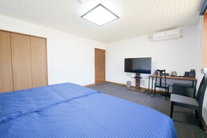 Ein Hotelzimmer mit einem Bett, einem Schreibtisch mit Stuhl, einem Fernseher und einer Klimaanlage.