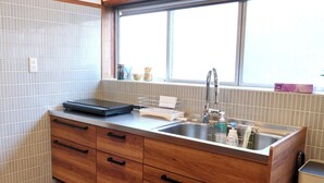 Eine Küche mit Spüle, Holzschränken, einem Fenster und einer Arbeitsplatte mit Wasserkocher.