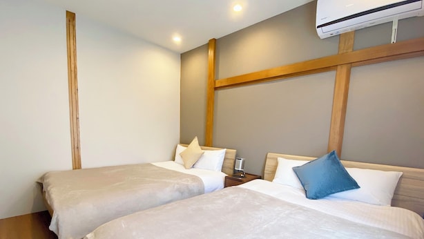 Ein Hotelzimmer mit zwei Betten, einem Holzkopfteil, einem Nachttisch mit Lampe und einer Klimaanlage.