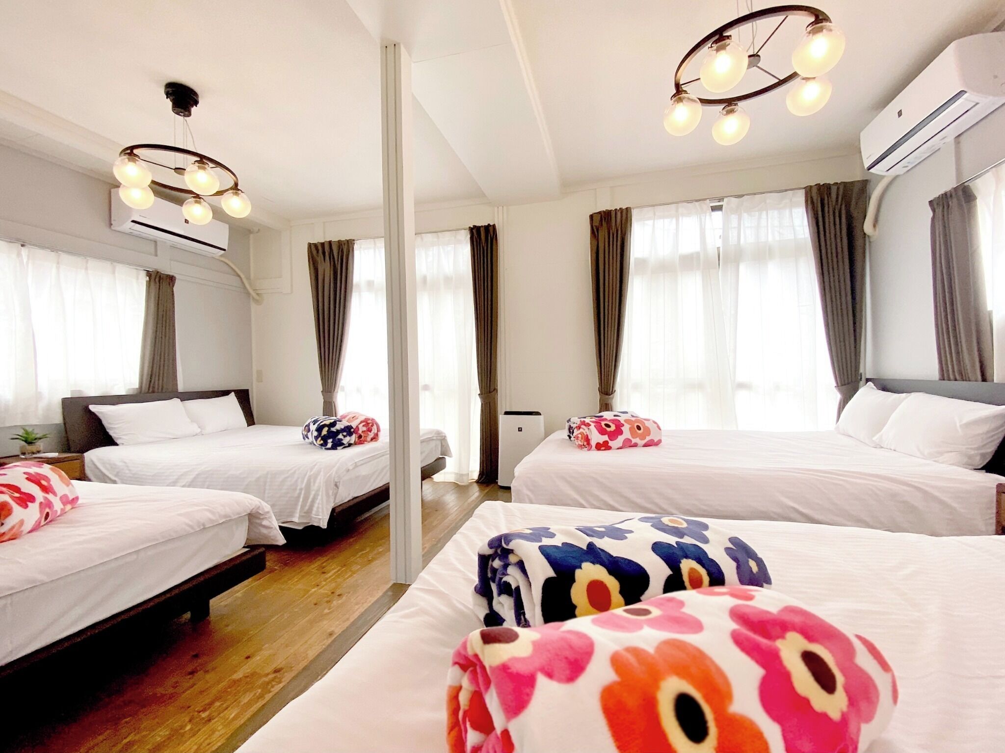 Ein Hotelzimmer mit zwei Betten, einer modernen Chandelüster und einer Klimaanlage.