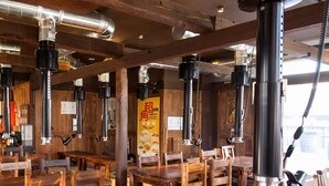 L’intérieur d’un restaurant, avec des tables et des chaises en bois, des conduits de ventilation en métal et un présentoir à menus.