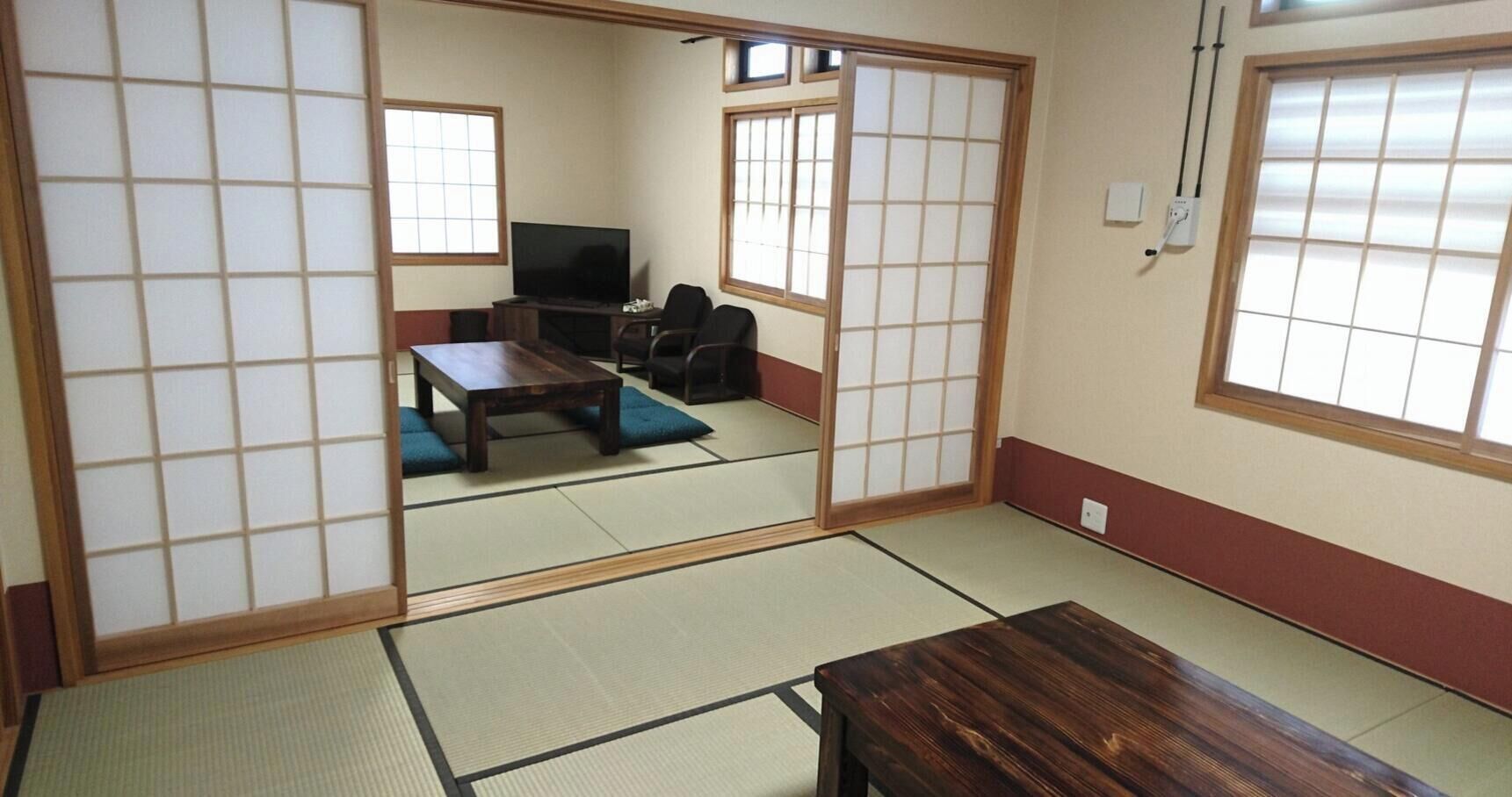 A traditional Japanese room with tatami flooring, a low table, a sofa, and sliding doors.