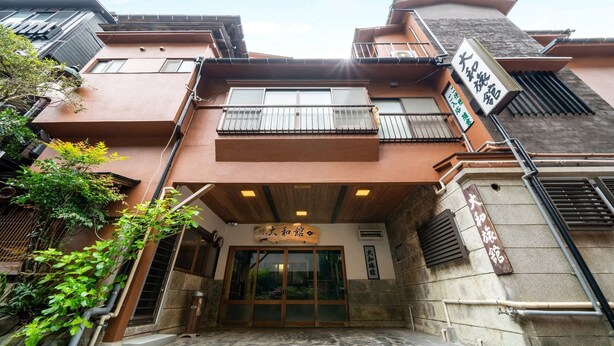 A traditional Japanese building with a wooden entrance, a signboard, and a small garden area. - Hakone Yumoto Onsen Ryokan Yamatokan (Hakone)