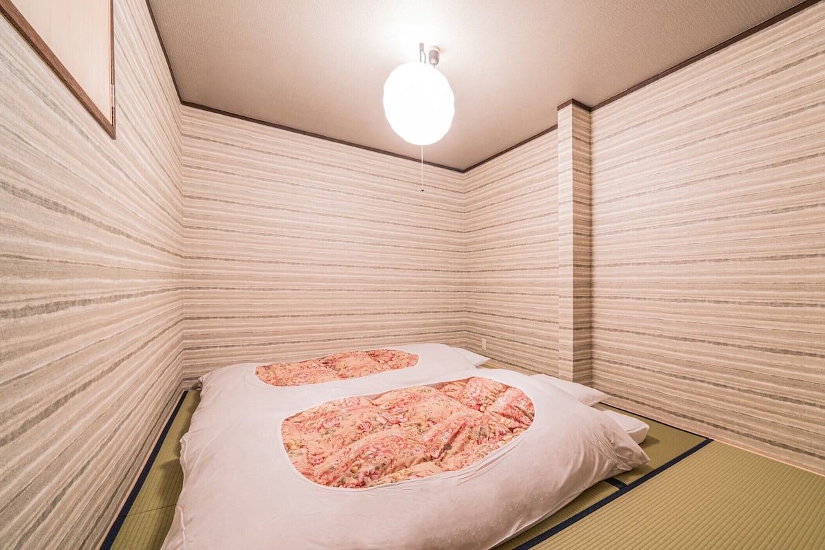 Ein Zimmer mit einem Bett, einer Deckenleuchte und Holzwänden.