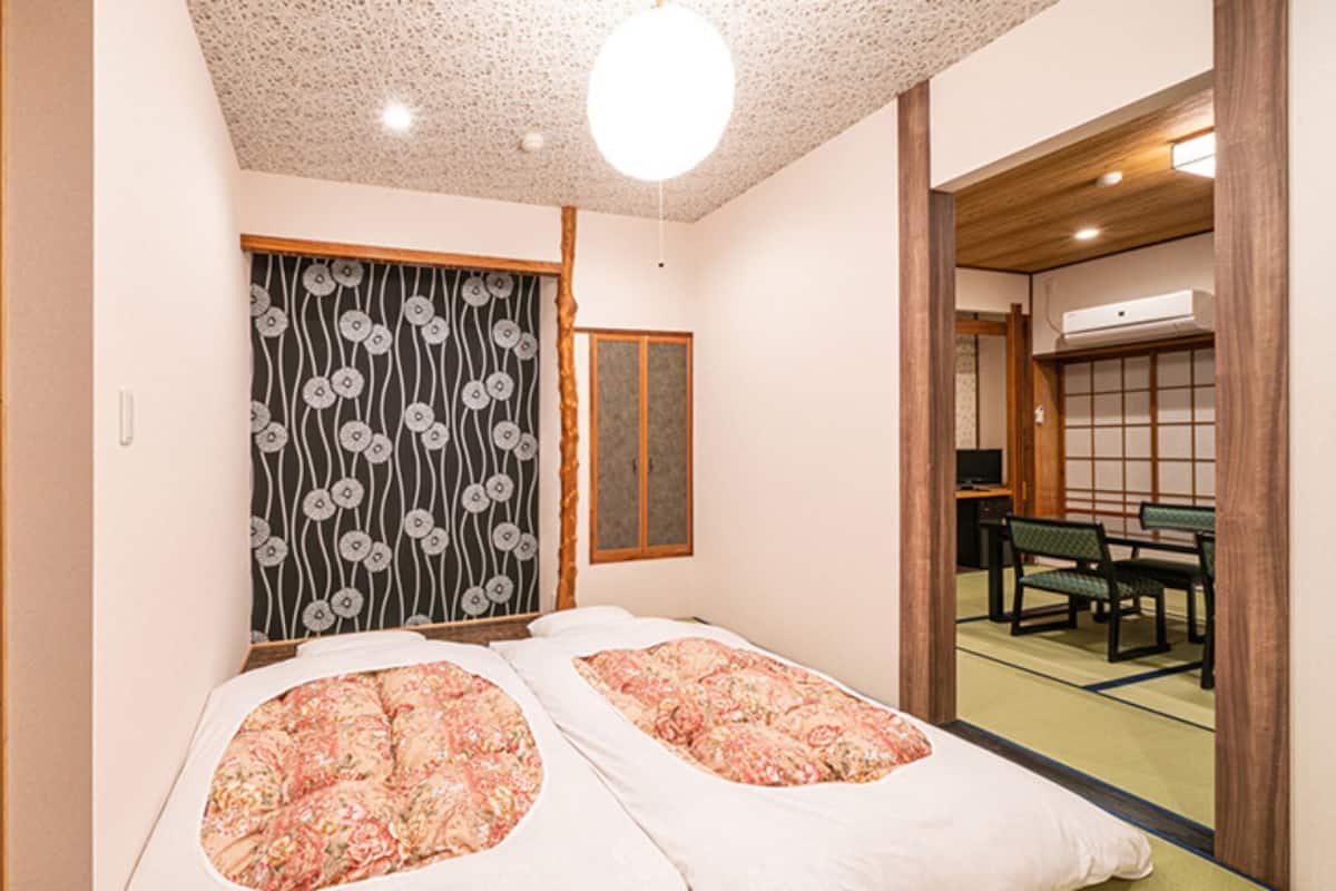 Ein traditioneller japanischer Raum mit Tatami-Boden, Futon-Bett, Shoji-Schirmwänden und einer Schiebetür.