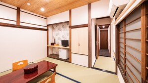 A traditional Japanese-style room with tatami flooring, a wooden table, a television, and sliding doors. - Hakone Yumoto Onsen Ryokan Yamatokan (Hakone)