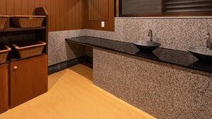 A modern bathroom with wooden paneling, a granite countertop, a sink, and a window with blinds. - Hakone Yumoto Onsen Ryokan Yamatokan (Hakone)