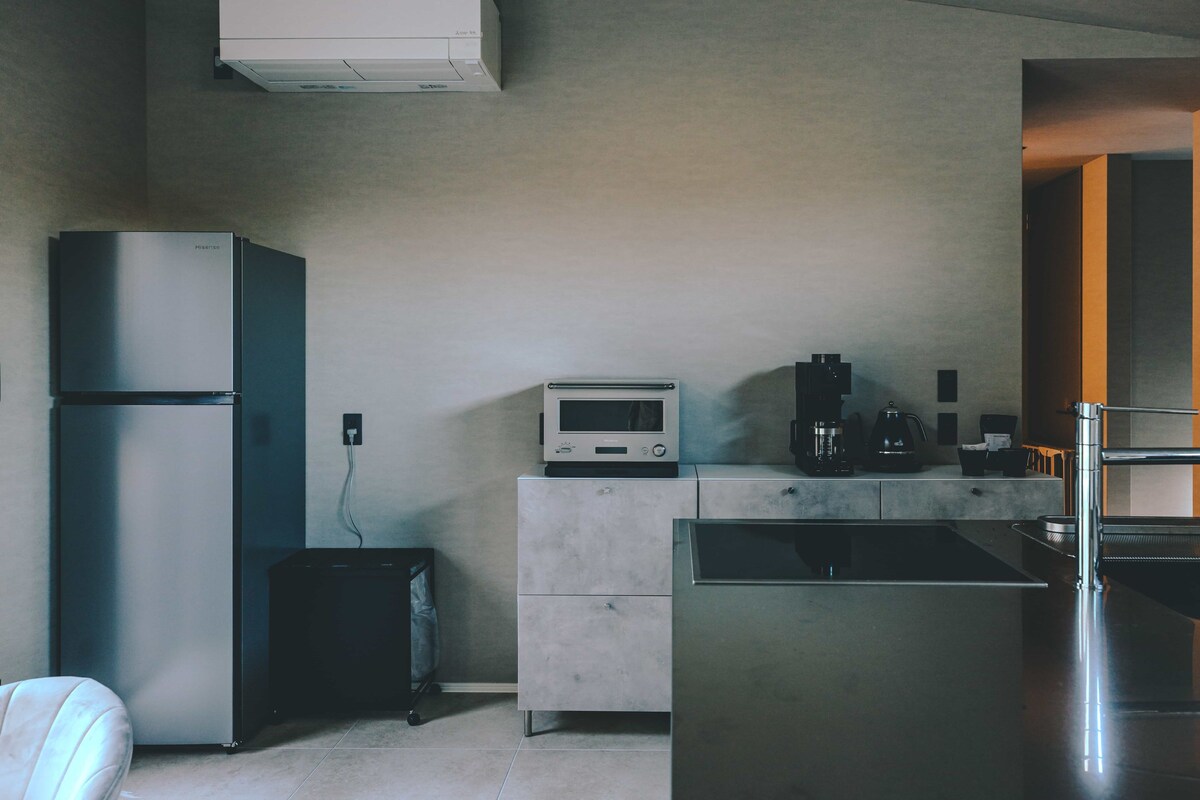Una cocina moderna con un refrigerador de acero inoxidable, microondas y cafetera.