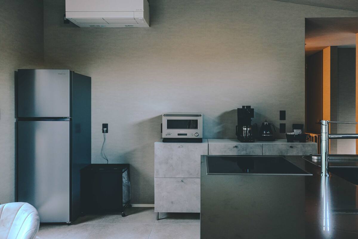 Une cuisine moderne équipée d’un réfrigérateur, d’un four à micro-ondes et d’une machine à café, tous en acier inoxydable.