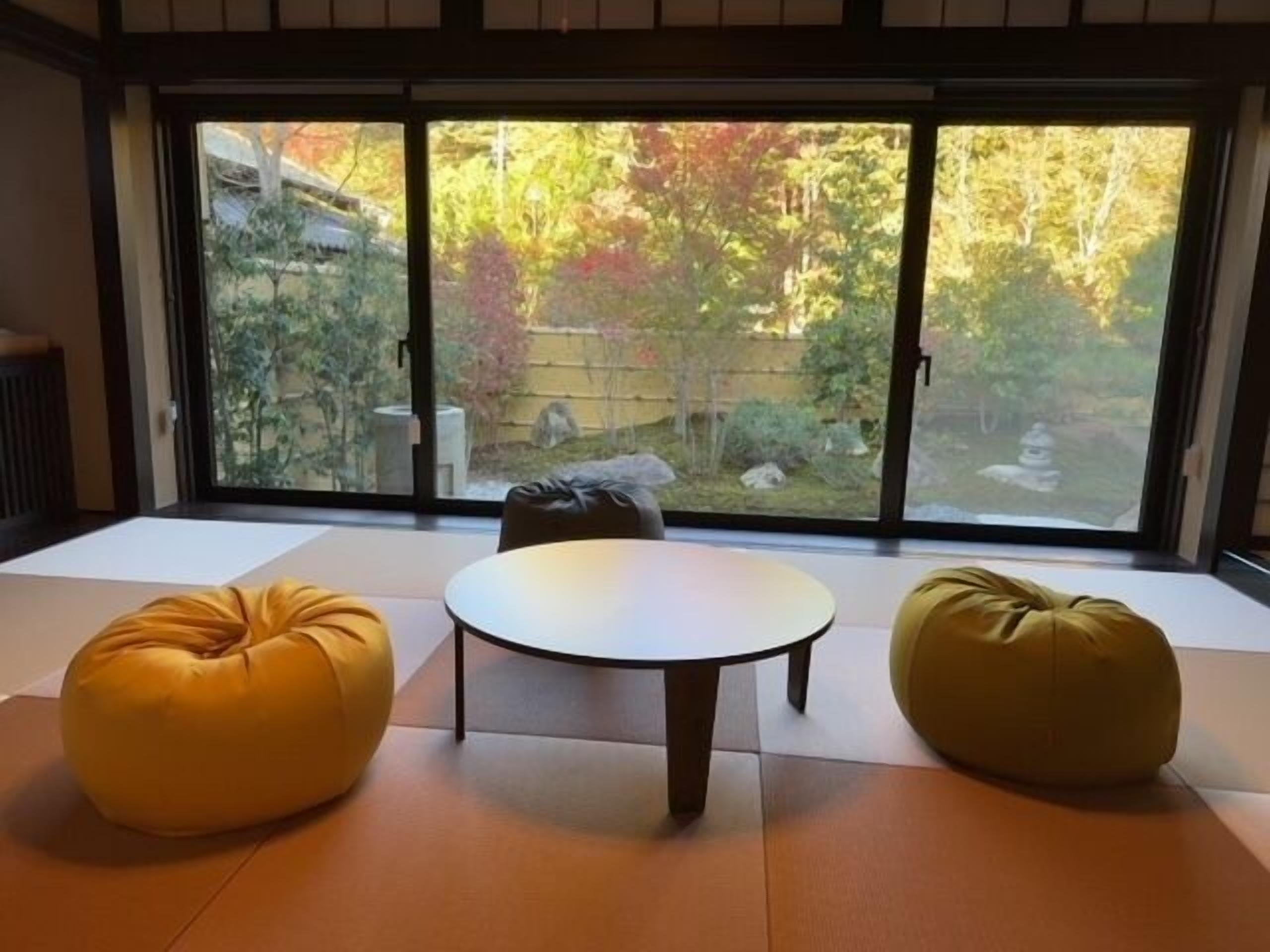 A room with tatami flooring, a round table, and two bean bag chairs.