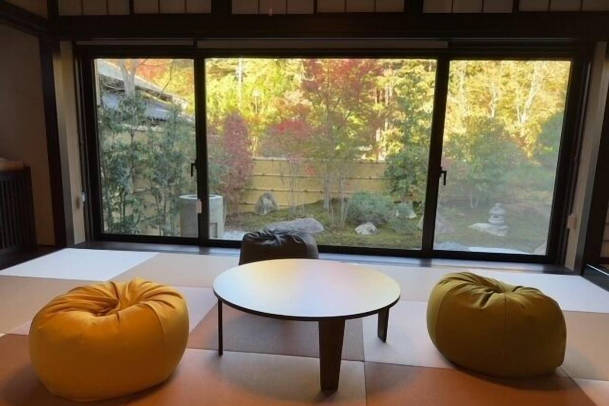 Una habitación con suelo de tatami, una mesa redonda y dos sillones tipo orejero.