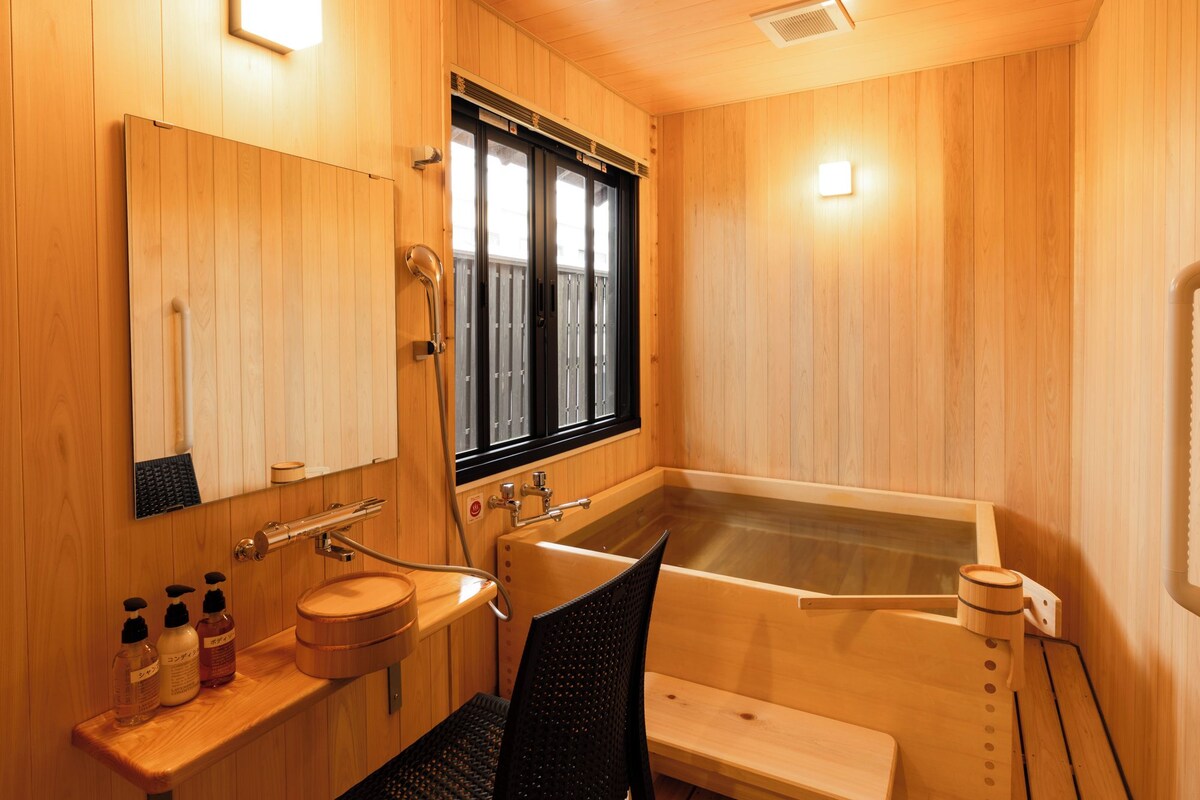 A wooden-finished bathroom with a bathtub, a sink with a mirror, and a window.