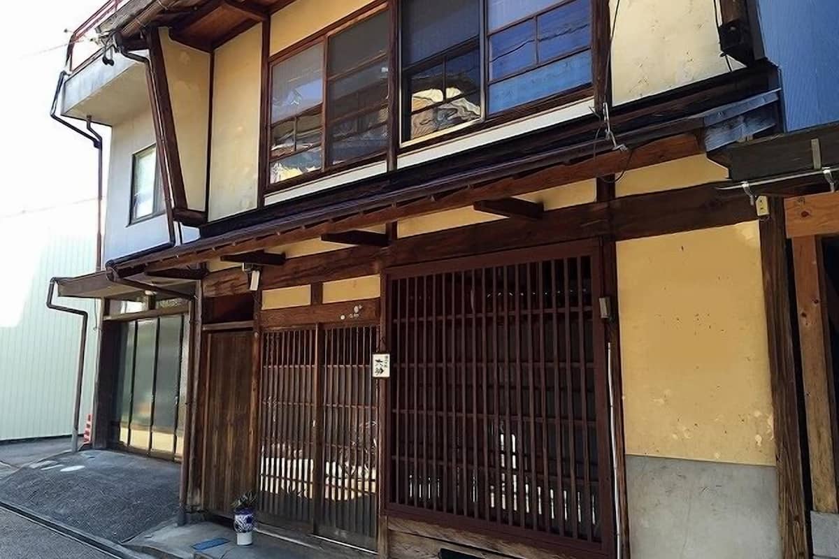 A traditional Japanese house with a wooden structure, sliding doors, and a small garden area.