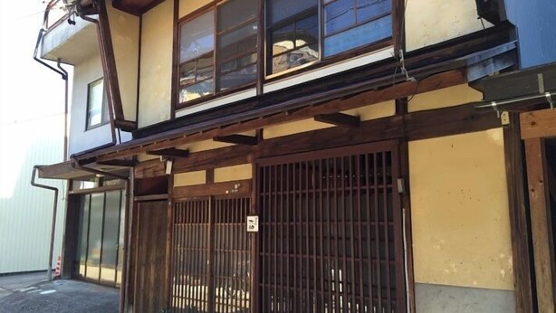 A traditional Japanese building with a wooden structure, sliding doors, and a small entrance area.