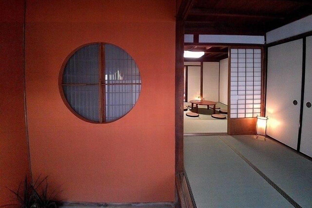 A traditional Japanese room with tatami flooring, a shoji screen, and a circular window.