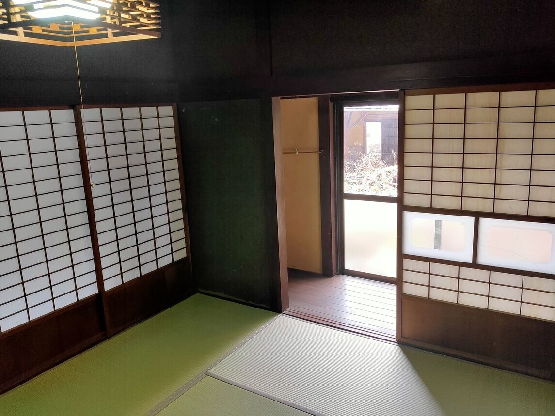 Ein traditioneller japanischer Raum mit Tatami-Bodenbelag, Shoji-Schirmwänden und einer Schiebetür, die auf einen Balkon führt.