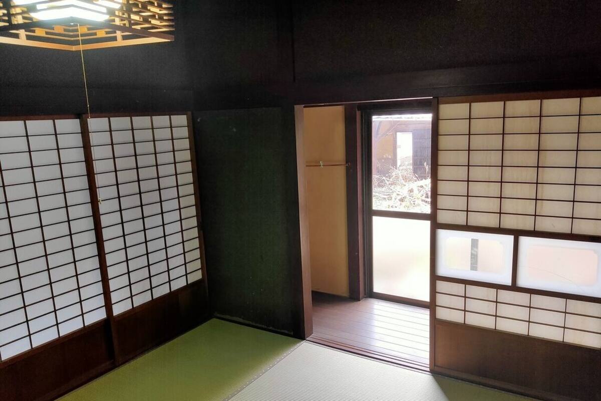 Una habitación japonesa tradicional con suelo de tatami, puertas shoji y un acceso corredizo a un balcón.