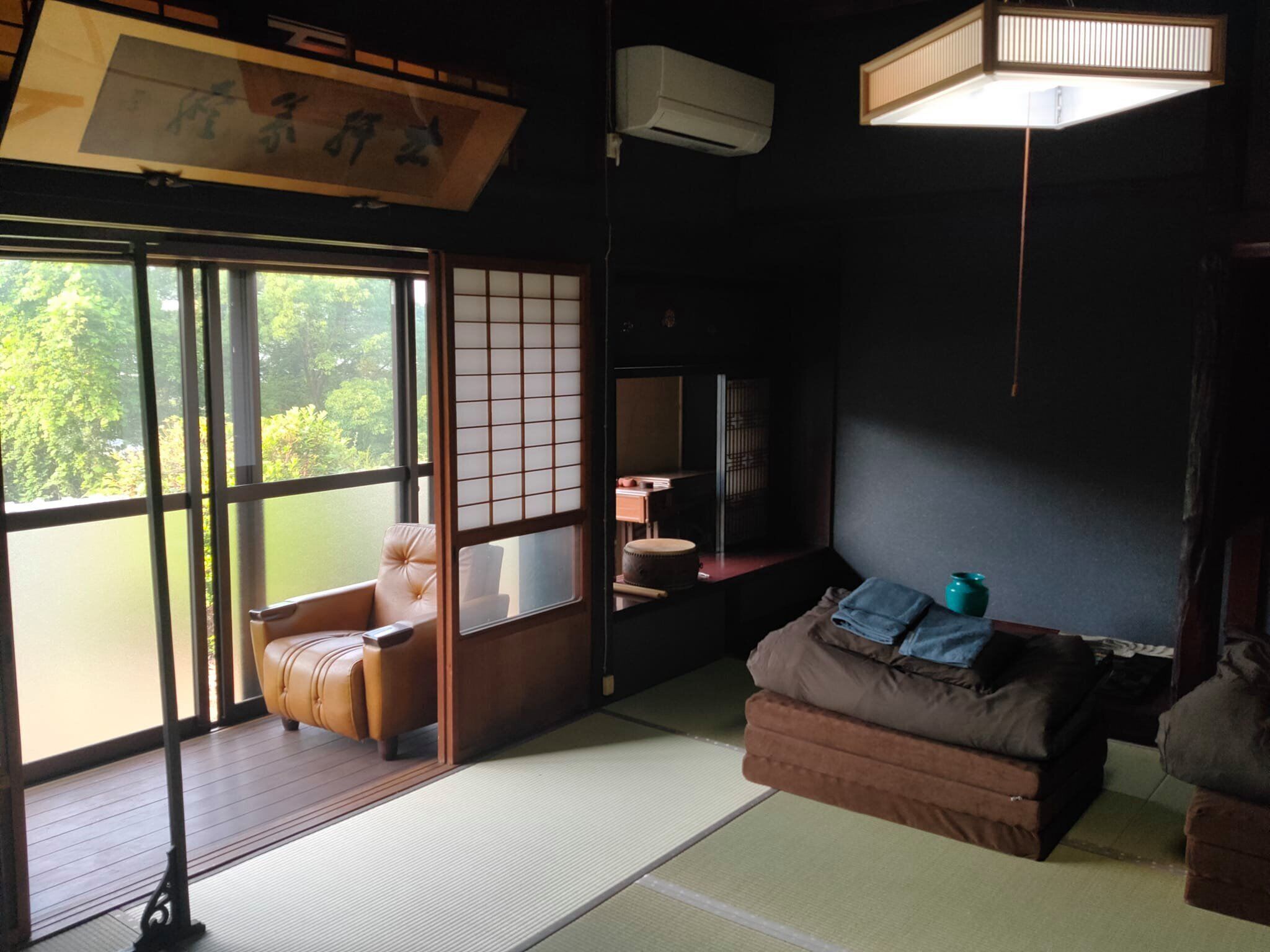 Ein traditioneller japanischer Raum mit Tatami-Böden, einer verschiebbaren Shoji-Trennwand, einer gepolsterten Sitzecke und einem Fernseher.