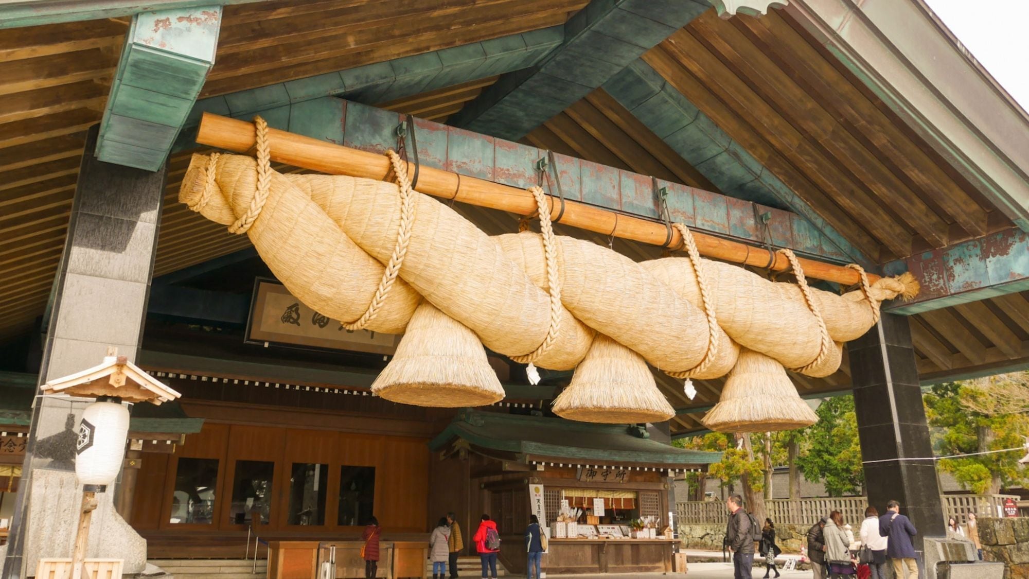A traditional building with a wooden structure, a stone statue, and a sign with Japanese characters.