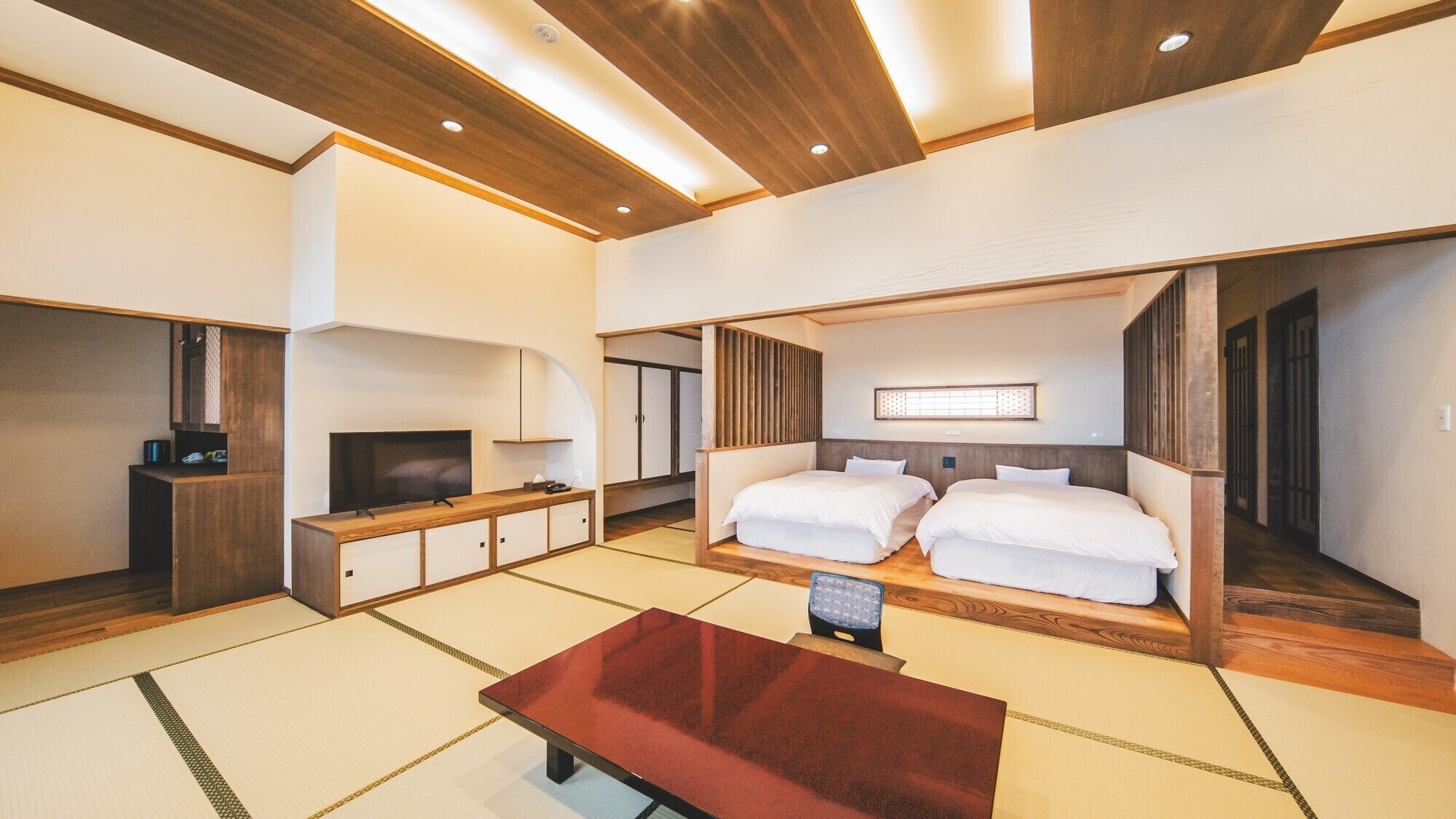 Quarto de hotel moderno com televisão, escrivaninha de madeira, sofá e uma cama grande.