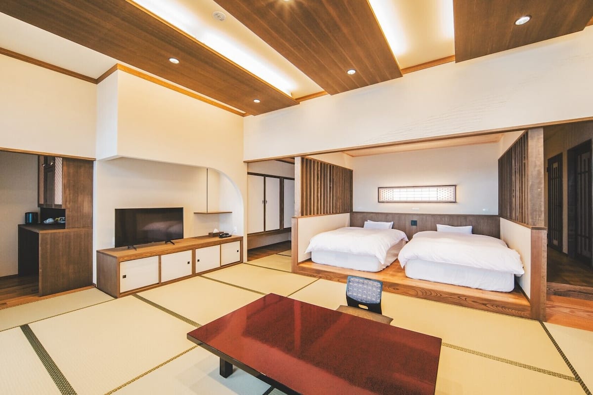 Una habitación de hotel moderna con televisión, escritorio de madera, sofá y una cama grande.