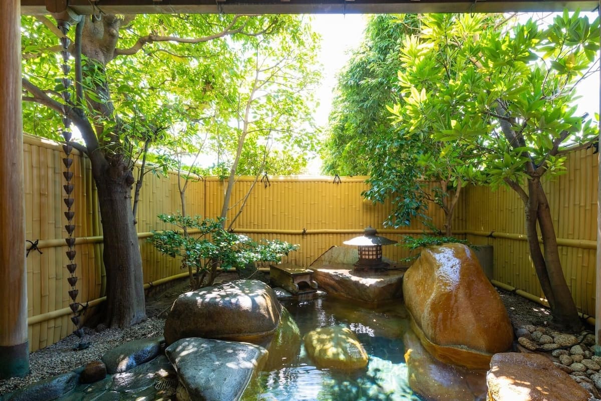 A tranquil garden with a water feature, bamboo fencing, and a traditional Japanese lantern.