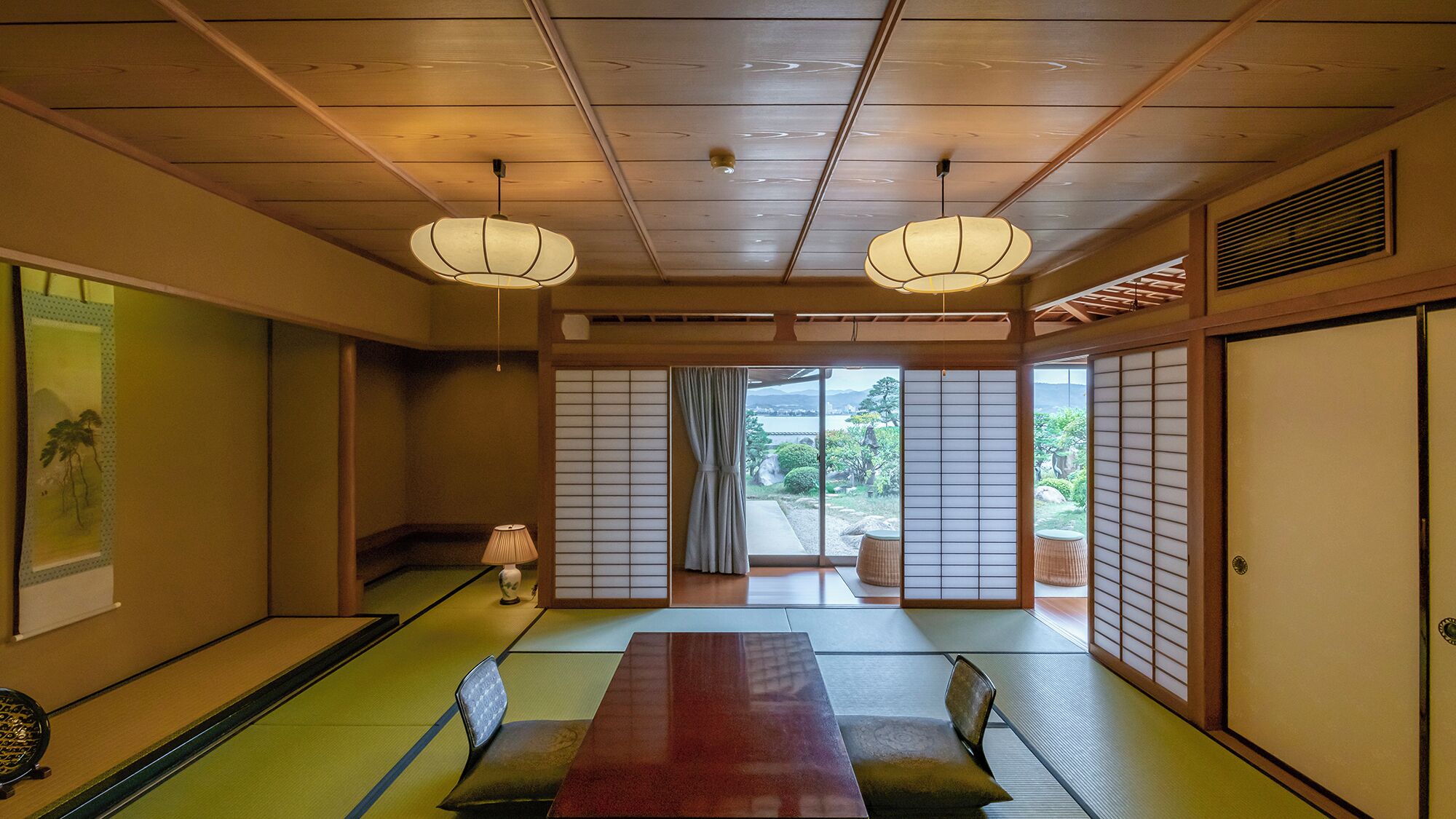 Um quarto japonês tradicional com piso de tatame, painéis shoji e uma mesa baixa com almofadas.