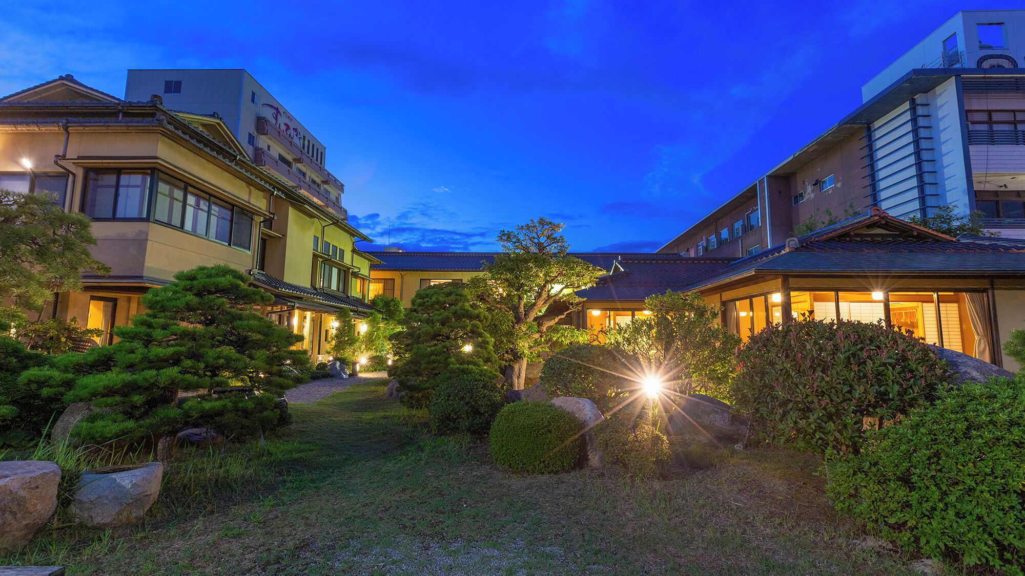 A traditional Japanese-style building with a well-maintained garden, including rocks and trees.