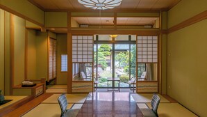 Una habitación japonesa tradicional con suelo de tatami, una mesa baja y puertas correderas que dan a un jardín.