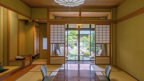 Een traditionele Japanse kamer met tatami vloerbedekking, een lage tafel en schuifdeuren die uitkomen op een tuin.