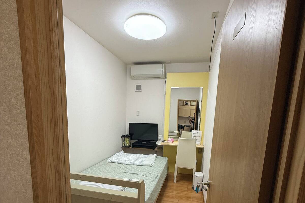 Un dormitorio con cama, escritorio, silla y televisor.