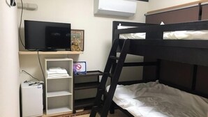 A bunk bed room with a television, a small shelf, and a desk. - Minshuku Warakuya (Kobayashi)