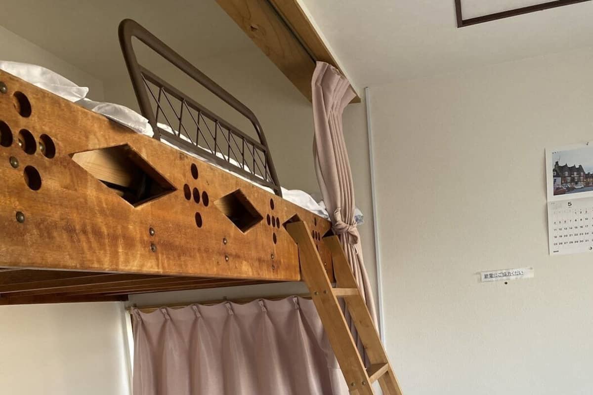 Una cama litera con escalera, una mesita con superficie de vidrio y un calendario en la pared.