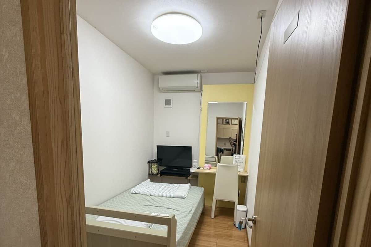 Un dormitorio con cama, escritorio, silla y televisión.