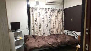 A room with a bed, a TV on a shelf, and a curtain with a leaf pattern. - Minshuku Warakuya (Kobayashi)