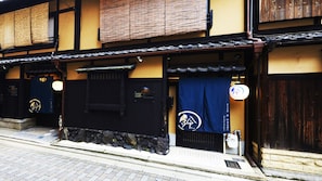 A traditional Japanese building with a stone base, wooden beams, and a tiled roof. - Rinn Shijo Takasegawa (Kyoto)