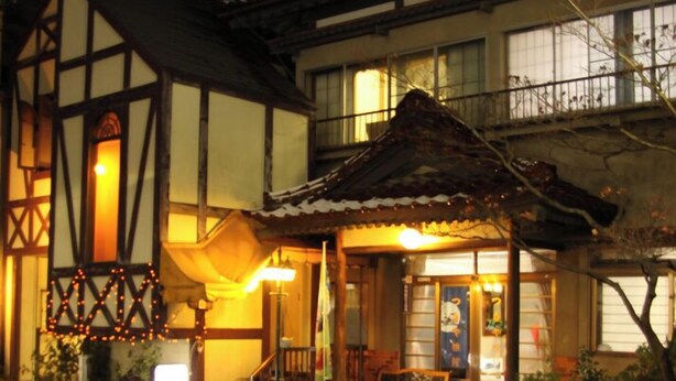A traditional Japanese building with a wooden exterior, a tiled roof, and a small porch with a bench. - Tsutaya Ryokan (Kuji)
