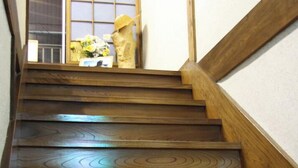 A wooden staircase with a handrail, leading to a room with a window and a door. - Tsutaya Ryokan (Kuji)