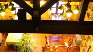 A staircase leading to a dining area with wicker chairs, a table, and a potted plant. - Tsutaya Ryokan (Kuji)