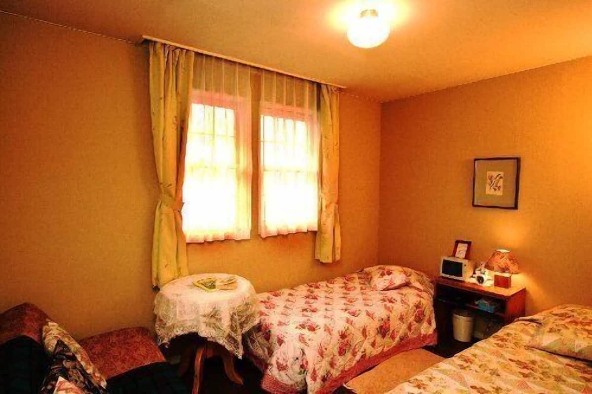 Ein Schlafzimmer mit zwei Betten, einem kleinen Tisch und einem Nachttisch mit Lampe.