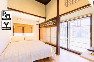 Habitación de hotel con cama, puerta corrediza al exterior y vista a la calle.