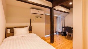 Quarto com cama, escrivaninha e ar condicionado.