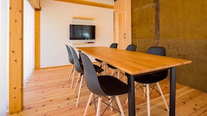 A conference room with a wooden table, black chairs, and a television on the wall. - Farmstay Miyuki-dori Goen (Ukiha)