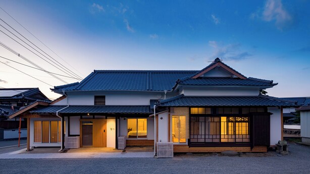 Uma casa japonesa tradicional com telhado de telhas, estrutura de madeira e um pequeno alpendre.