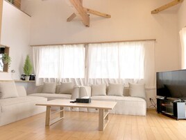 Una sala de estar con un sofá, una mesa de centro, un televisor y una ventana con cortinas.