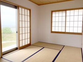 Una habitación con suelo de tatami, puertas correderas y una ventana con diseño de cuadrícula.